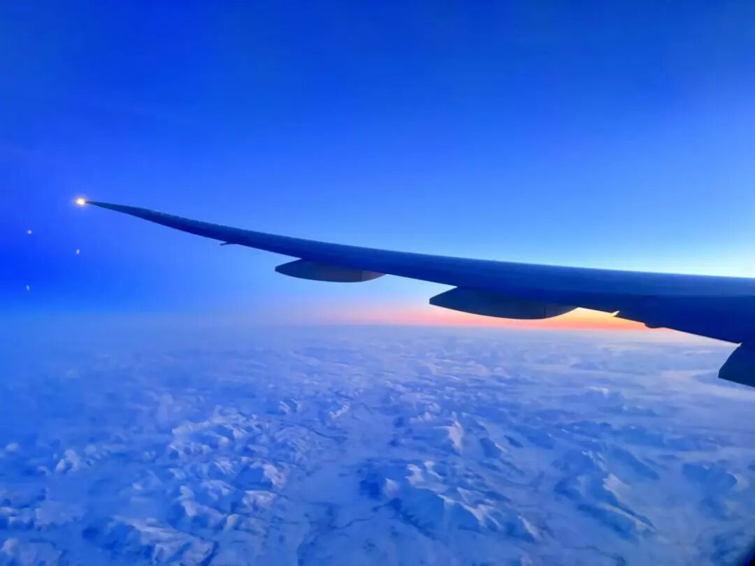 机窗外阿拉斯加上空冰川与橙色霞光