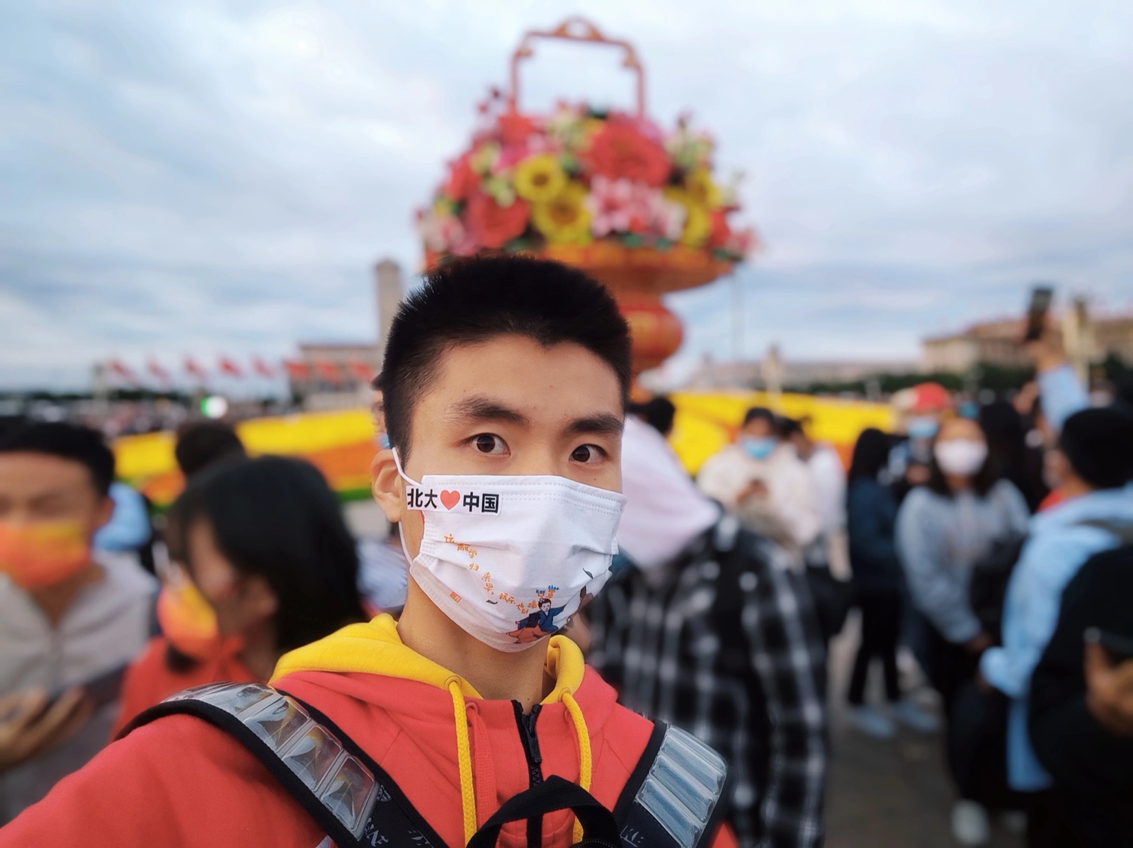 天安门广场前戴口罩少年与花篮装置自拍