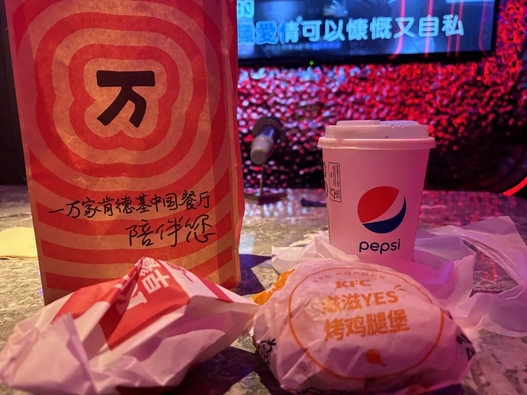 考后在肯德基用餐,KFC 烤鸡腿堡和百事可乐摆在 KTV 包间桌上